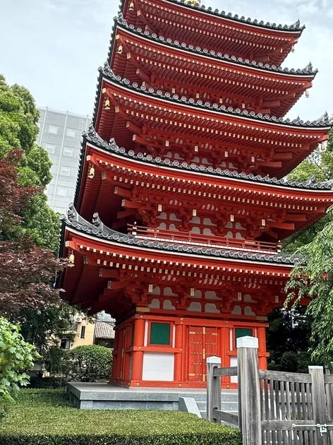 Die rote fünfstöckige Pagode des Tochoji-Tempels in der Altstadt von Hakata, eingerahmt von grünen Bäumen