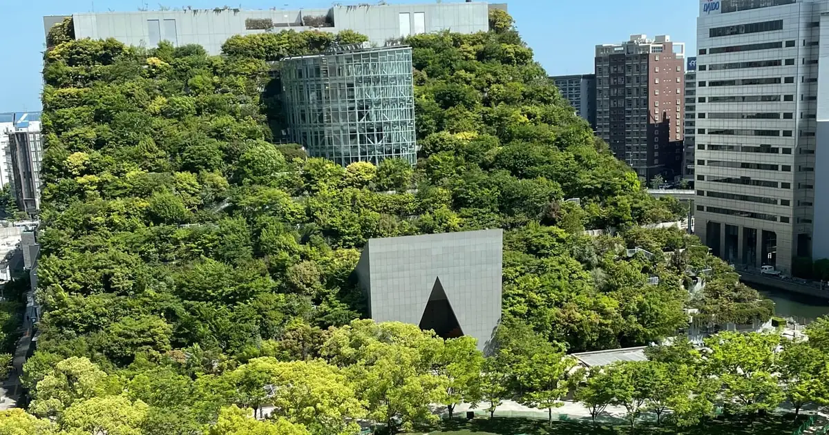 Le terrazze verdi a gradoni di ACROS Fukuoka accanto a palazzi di uffici a Tenjin