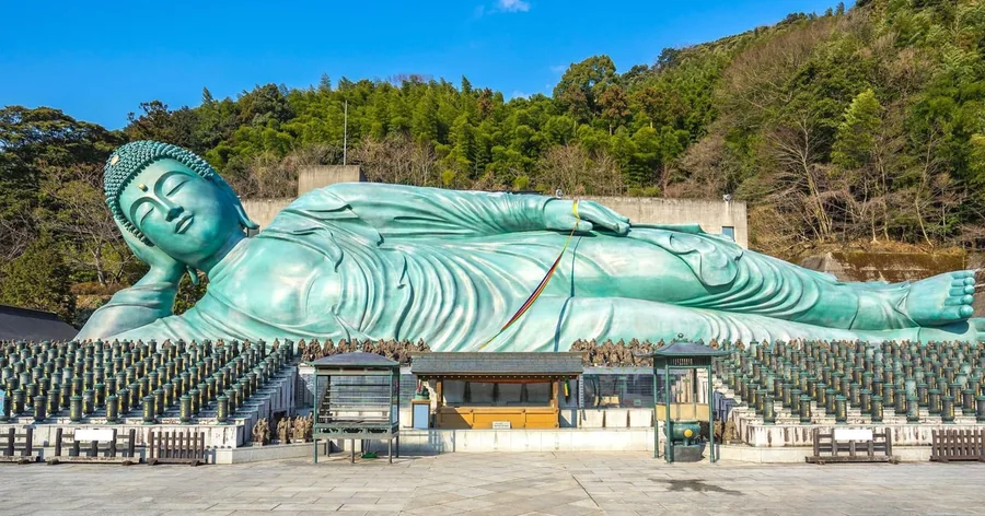 Der riesige liegende Bronze-Buddha des Nanzoin über Reihen kleiner Steinfiguren